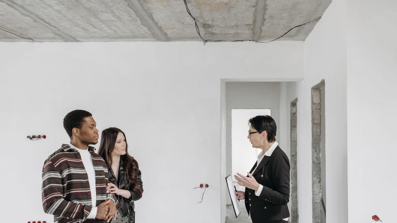 Two people walking through a home with a professional holding a clipboard
