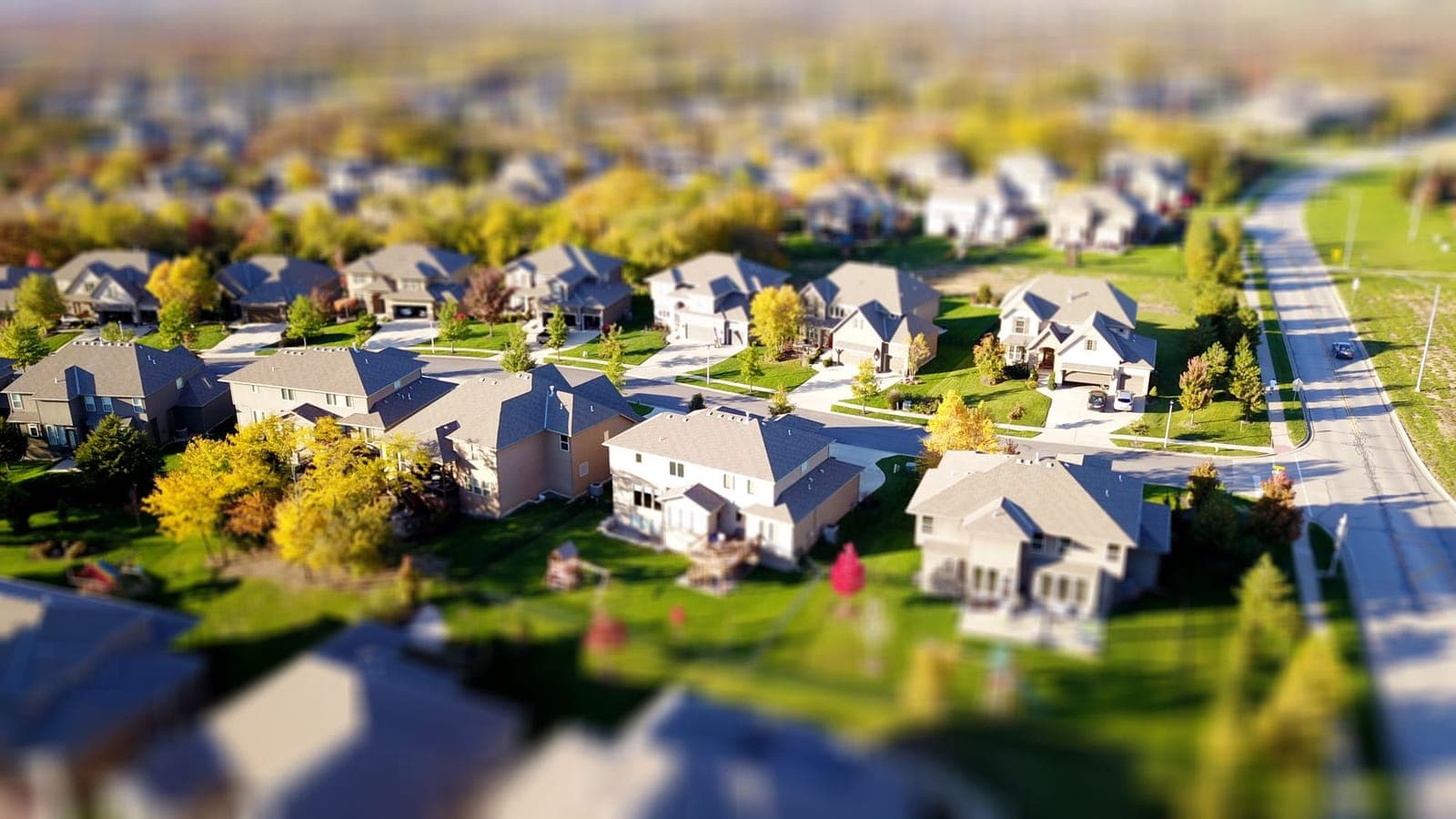 An aerial view of a neighborhood of homes with green lawns and tree lined streets